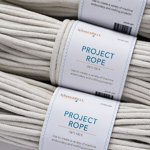 Puede incluir: Primer plano de tres carretes de cuerda de proyecto blanquecina. Cada carrete está etiquetado con "PROJECT ROPE" y la marca Kimberbell. La etiqueta indica que la cuerda mide 0,64 cm y 30,48 m de largo. El texto de la etiqueta dice: "¡Úselo para crear una variedad de proyectos de bordado y manualidades a máquina!"