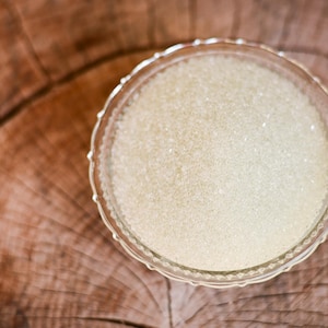 May include: A clear glass bowl filled with white sugar crystals.