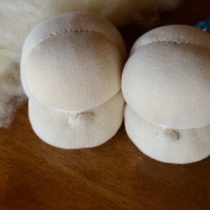 Puede incluir: Dos cabezas de mu&ntilde;eca de tela blanca con una superficie texturizada. Las cabezas est&aacute;n apiladas una encima de la otra.
