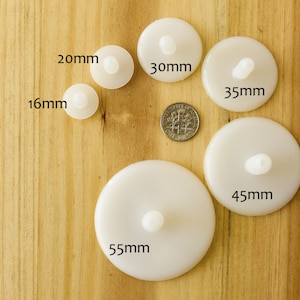 May include: A set of six white plastic circles with a small raised center, ranging in size from 16mm to 55mm. The circles are arranged in a semi-circle on a wooden surface.