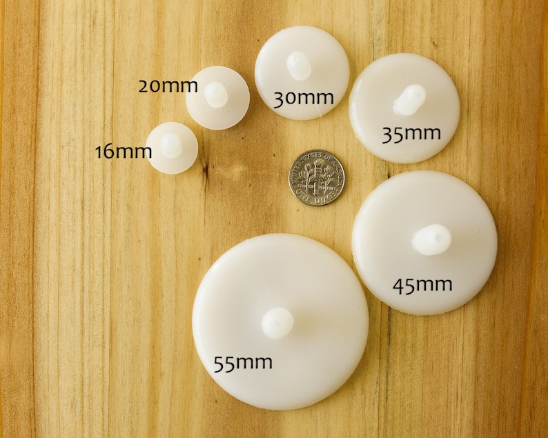 K&ouml;nnte beinhalten: Ein Satz von sechs wei&szlig;en Plastikkreisen mit einer kleinen erhabenen Mitte, die von 16 mm bis 55 mm reichen. Die Kreise sind in einem Halbkreis auf einer Holzoberfl&auml;che angeordnet.