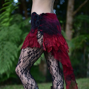 May include: A red and black layered skirt with a lace trim and a long, flowing train. The skirt is worn with black lace tights and brown boots.