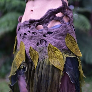 May include: A purple and green skirt with a layered design. The skirt is made of felt and has a unique, organic look. The skirt is decorated with leaves and has a cut-out design.