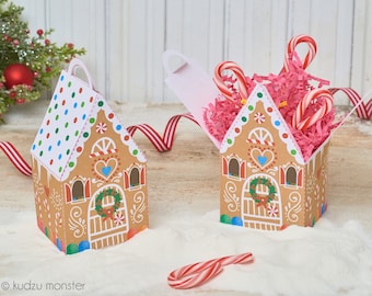 May include: Two gingerbread house shaped boxes, one with the lid open and filled with pink tissue paper and candy canes, the other closed. Both boxes have a white and brown gingerbread design with red and blue accents.