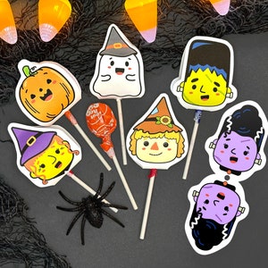 May include: A set of eight Halloween-themed lollipop toppers featuring a witch, a ghost, a pumpkin, a scarecrow, a Frankenstein, a vampire, and two mummies. The toppers are printed on white cardstock and have colorful details.