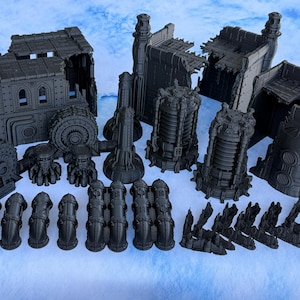 May include: A collection of dark gray, unpainted plastic miniature terrain pieces for tabletop gaming. The set includes ruined building sections with arched windows, cylindrical industrial towers, various pipe segments, and small debris piles.