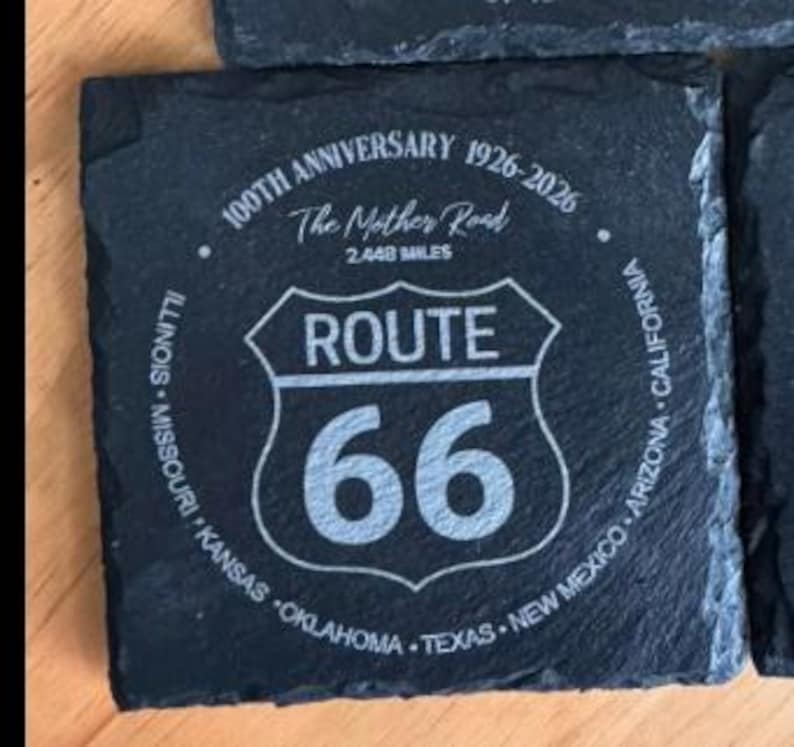 May include: Square, dark gray slate coaster with the Route 66 logo and text. The text includes "100TH ANNIVERSARY 1926-2026", "The Mother Road", "2,448 MILES", and the names of states along the route. The Route 66 logo is in the center.