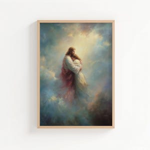 May include: Framed artwork depicting a tender embrace. A figure in white and red robes embraces another in a flowing white gown, set against a backdrop of ethereal clouds and soft light. The artwork is framed in a light-colored wooden frame.