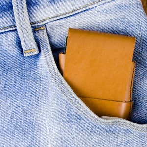 Puede incluir: Una cartera de cuero marr&oacute;n en el bolsillo delantero de unos vaqueros azules.