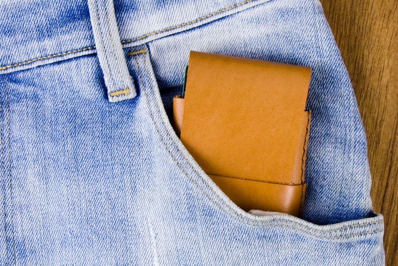 Puede incluir: Una cartera de cuero marr&oacute;n en el bolsillo delantero de unos vaqueros azules.