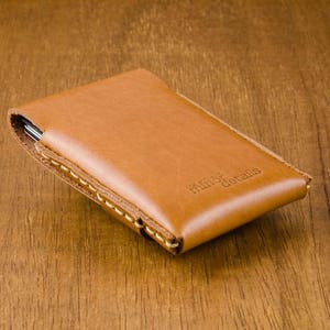May include: A brown leather wallet with a stitched edge and the text "minor details" embossed on the front.