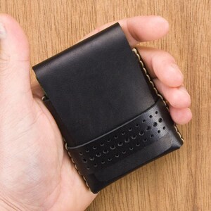 May include: A black leather wallet with a perforated design and a light brown stitch detail.