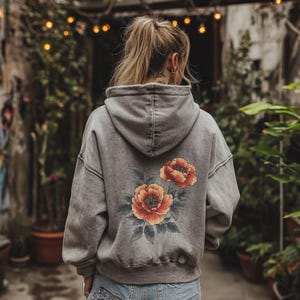 May include: A gray hooded sweatshirt with a floral print on the back. The flowers are red, orange, and green.