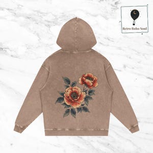 May include: A brown hoodie with a floral design on the back. The flowers are red, orange, and yellow with green leaves.