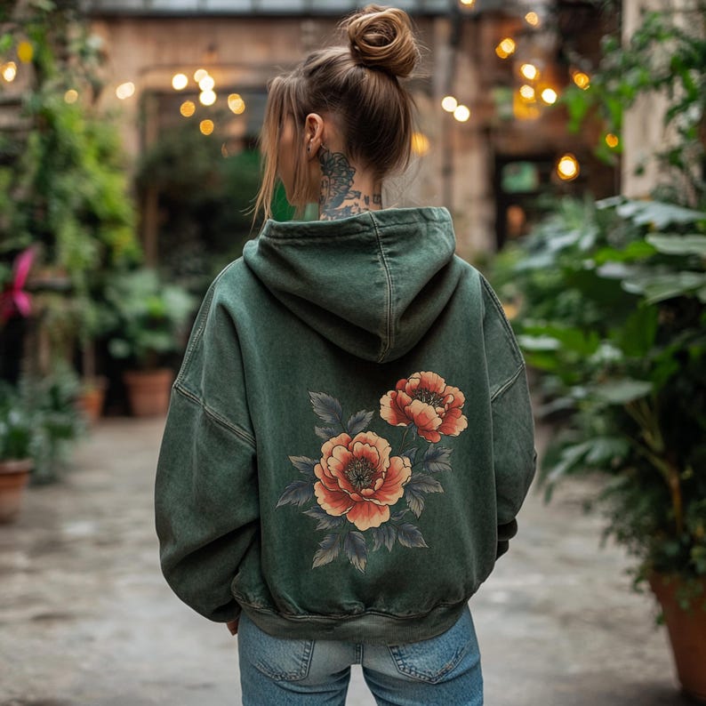 May include: A dark green hooded sweatshirt with a floral print on the back. The flowers are red and orange with green leaves.