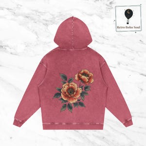 May include: A maroon hoodie with a floral design on the back. The flowers are orange and yellow with green leaves.