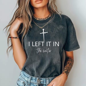 A woman wearing a black t-shirt with the text "I LEFT IT IN THE WATER" printed on it.