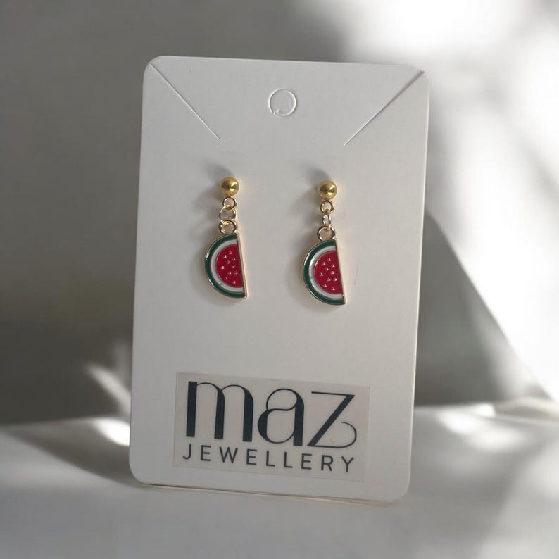 K&ouml;nnte beinhalten: Ein Paar goldene Wassermelonen-Schnitz-Ohrringe auf einer wei&szlig;en Karte mit dem Text "maz jewellery".