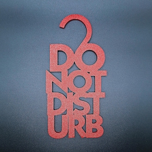 May include: A red, glittery "DO NOT DISTURB" door hanger. The text is vertically stacked, with a curved hook at the top for hanging. The background is a solid, dark gray.