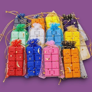 May include: A collection of twelve rectangular fidget toys, each composed of eight connected plastic cubes, individually packaged in sheer drawstring pouches decorated with gold star and crescent moon patterns in various colors.