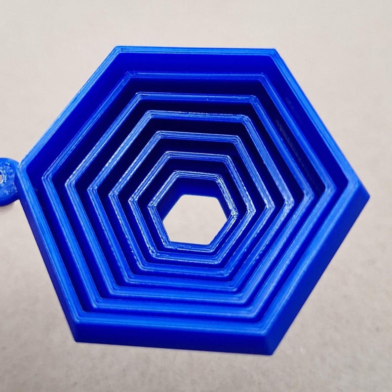 Handmade and customizable hex fidget keychains shown in cobalt blue, featuring colorful designs, perfect for kids birthday parties, classroom prizes, sensory play, and party favor gifts.