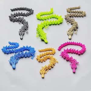 May include: Six articulated dragon figurines in black, neon green, metallic gold, blue, yellow, and hot pink. Each dragon features a segmented, flexible body with detailed scales, a distinct head with horns, and small limbs, arranged in a grid.
