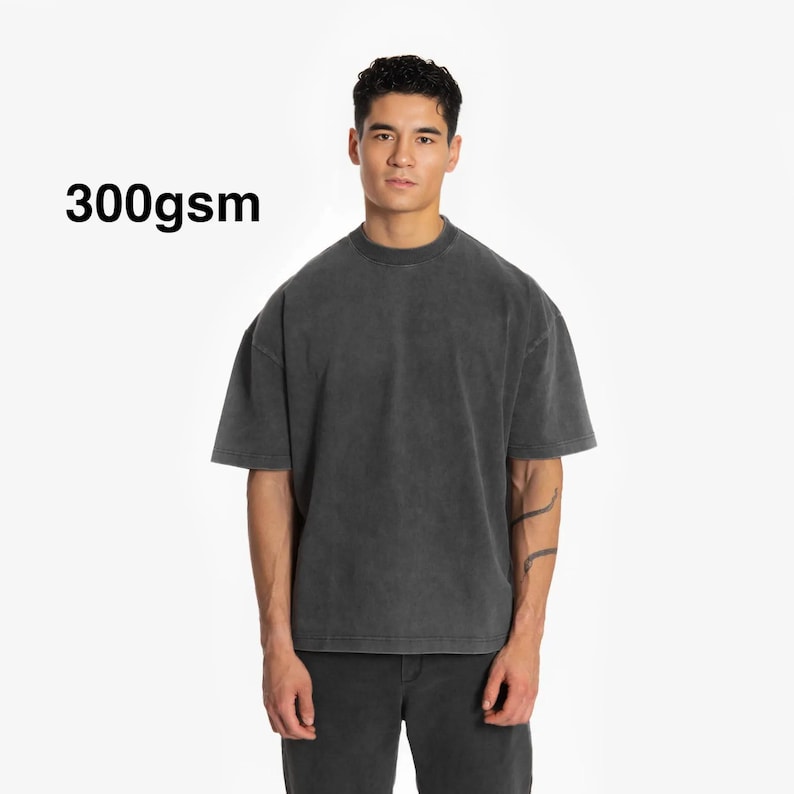 May include: A dark gray, oversized t-shirt with a 300gsm weight. The t-shirt has a relaxed fit and a crew neck.