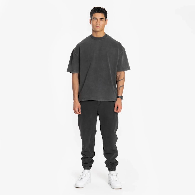 May include: A black oversized t-shirt with a faded look, paired with black jogger pants and white sneakers.
