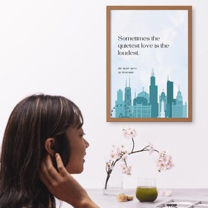 K&ouml;nnte beinhalten: Ein gerahmter Druck mit einem blauen und wei&szlig;en Stadtbild im Hintergrund. Der Druck zeigt das Zitat "Sometimes the quietest love is the loudest." in schwarzem Text. Das Zitat wird "The Right Move" von Liz Romano zugeschrieben.