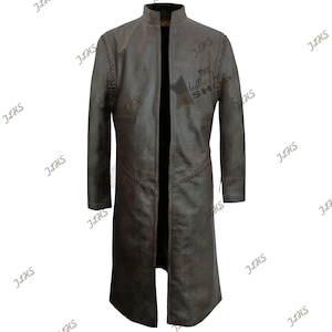 Pode incluir: Um casaco longo de couro castanho desgastado com gola mandarim. O casaco apresenta costuras decorativas ao longo das costuras e dos ombros. O texto "THE leather shop" é visível no peito.