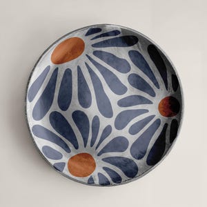 May include: A round ceramic plate with a blue and white floral pattern. The flowers have orange centers.