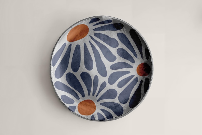 May include: A round ceramic plate with a blue and white floral pattern. The flowers have orange centers.