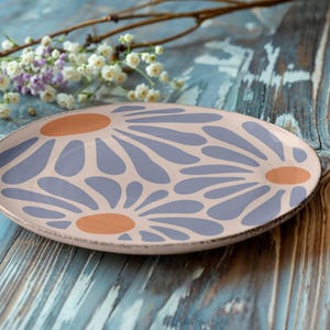 May include: A ceramic plate with a floral design. The plate is pink with purple and orange flowers.