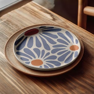 May include: A white ceramic plate with a blue and orange floral pattern. The plate is on a wooden table.
