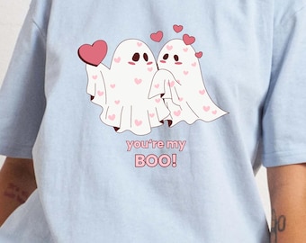 May include: Light blue t-shirt featuring a graphic of two cartoon ghosts holding hands and hearts. The text "you're my BOO!" is printed below the ghosts.