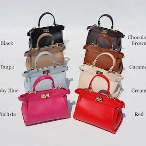 K&ouml;nnte beinhalten: Eine Sammlung von zehn Ledertaschen in verschiedenen Farben, darunter Schwarz, Taupe, Babyblau, Fuchsia, Rot, Creme, Karamell, Schokoladenbraun. Jede Tasche hat einen goldenen Verschluss und einen oberen Griff.