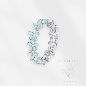 May include: A silver ring featuring a delicate design of light blue enamel flowers. The ring is marked with "S925" on the side.