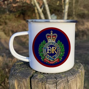 May include: White enamel mug featuring a red, blue and gold Royal Engineers crest. The crest includes a crown, a wreath of leaves and the letters "E.R." in gold.