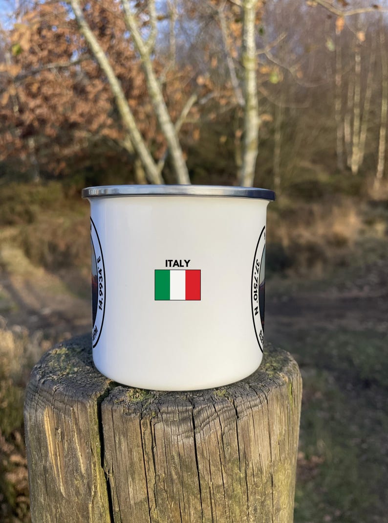 A 350ml White Enamel Mug with a circular logo displaying Mount Etna and the official coordinates and elevation. On the side of the mug is a Italian flag to show where the summit lies internationally!