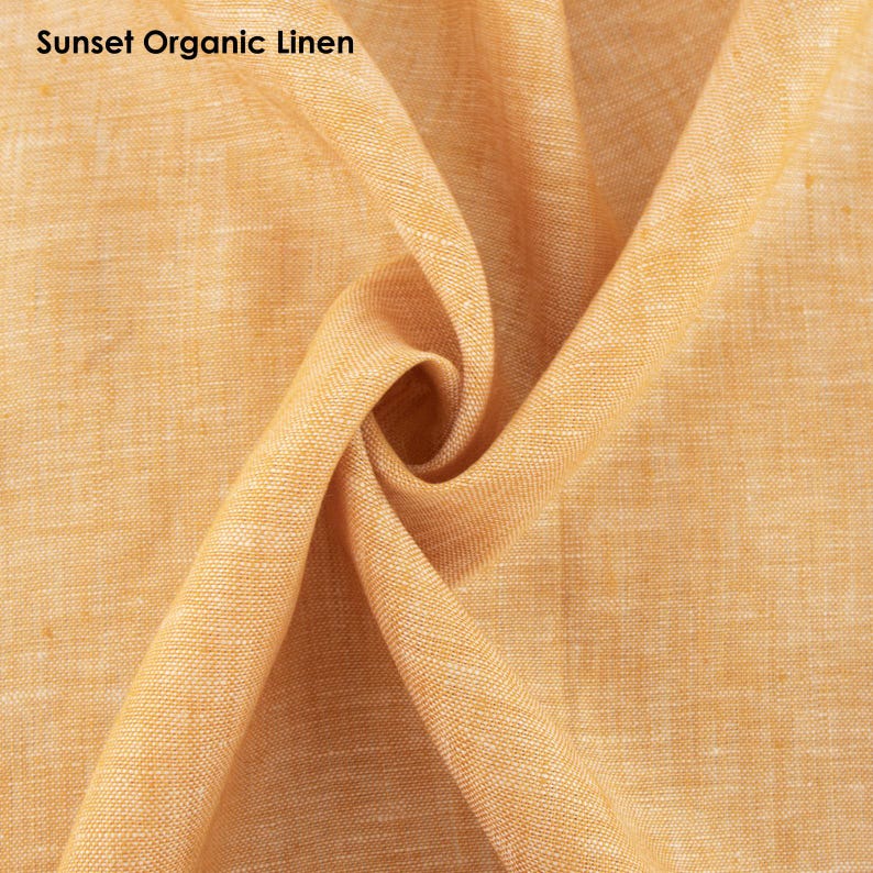 May include: Close-up of a textured, organic linen fabric in a warm sunset orange color. The fabric is folded and draped, showcasing its soft and natural texture.