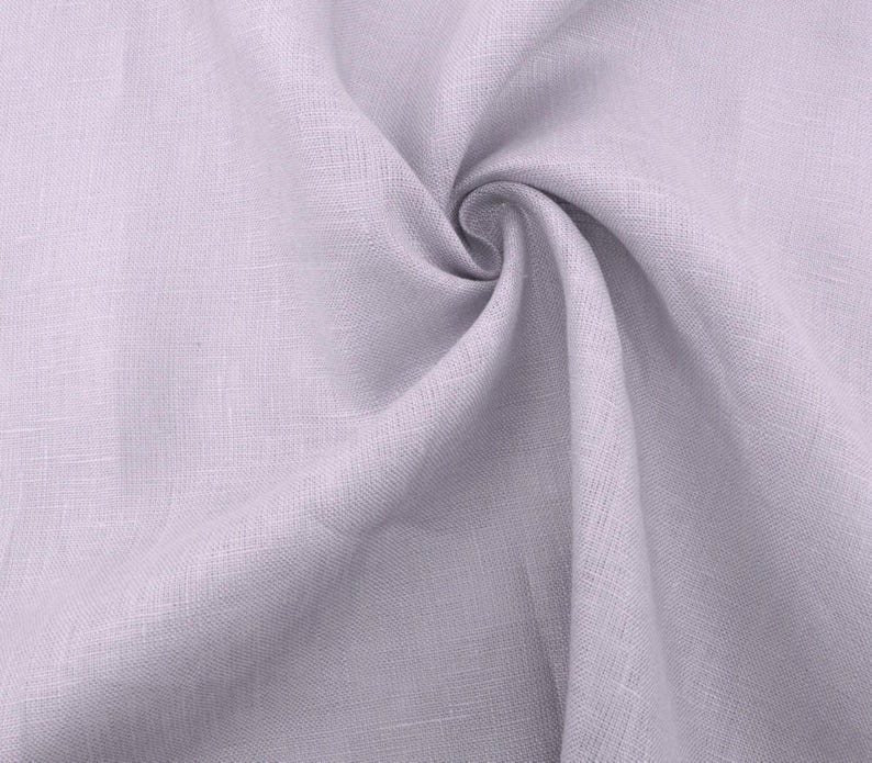 May include: A close-up of a light purple linen fabric with a soft, textured surface.