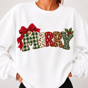 May include: A white long-sleeve sweatshirt featuring the word MERRY in large, stylized letters. Each letter has a different pattern, including green plaid, holly leaves, red with gold stars, leopard print, and a green knit texture, with a red bow.