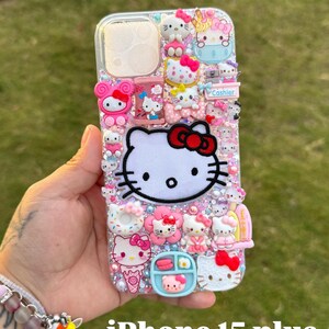Może przedstawiać: Przezroczyste etui na iPhone 15 Plus ozdobione postaciami Hello Kitty i innymi r&oacute;żowymi i białymi postaciami. Etui ma błyszczące tło i zawiera tekst "Cashier".