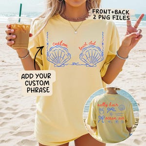 May include: A pale yellow t-shirt featuring a blue seashell design and the words "custom beach club". The back of the shirt displays the words "salty hair ocean air" with beach-themed graphics. The image also includes the text "ADD YOUR CUSTOM PHRASE".