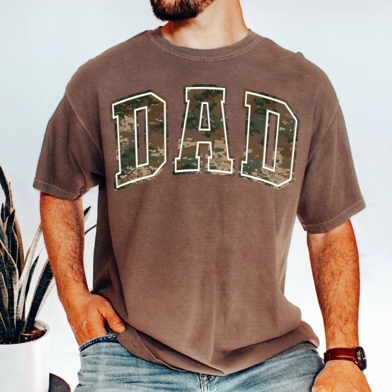 May include: A brown t-shirt with a camouflage print "DAD" graphic.