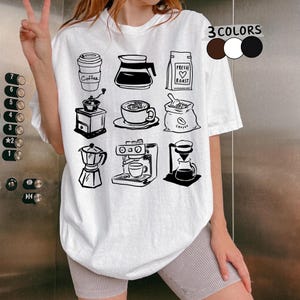 Könnte beinhalten: Weißes T-Shirt mit schwarzen Illustrationen von Kaffeeutensilien: einem Coffee-to-go-Becher, einer Kaffeekanne, einem Beutel mit Bohnen, einer Kaffeemühle, einer Kaffeetasse, einem Beutel mit Kaffeebohnen, einem Espressokocher, einer Espressomaschine und einem Filterkaffeezubereiter. Text: "3 COLORS".