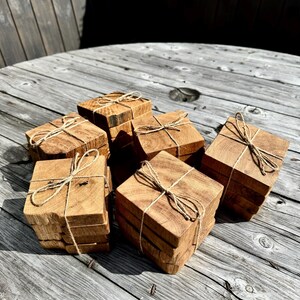 May include: Set of six wooden coasters, each tied with twine and stacked in groups of two or three. The coasters are made of natural wood with a rustic finish.