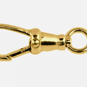May include: A gold-toned metal clasp with a swivel hook and a ring. The clasp is designed for attaching to a chain or strap.