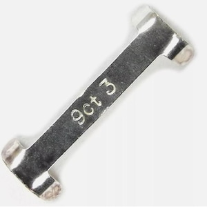 Puede incluir: Un componente de joyería de metal plateado con extremos redondeados. El texto "9ct 3" está grabado en la superficie. La pieza tiene forma rectangular con una ligera curva.