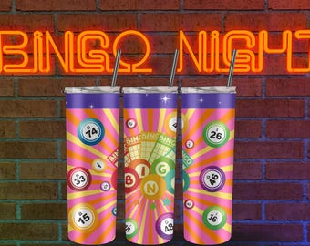 May include: Three pink and purple stainless steel tumblers with a bingo theme. The tumblers have a pink background with yellow and orange bingo balls and a bingo card design. The text "BINGO" is printed on the tumblers.